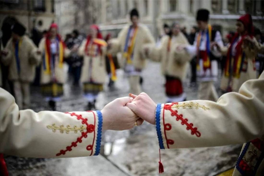 Dancers in traditional Romanian costume joining hands in a hora